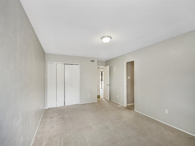 unfurnished bedroom with light colored carpet and a closet