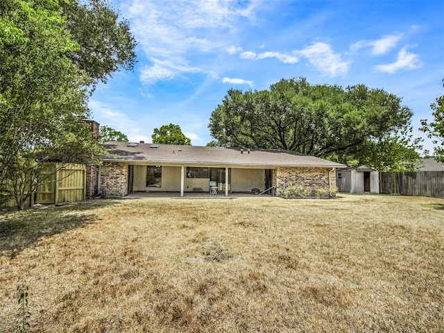 rear view of property featuring a lawn, a storage shed, and a patio