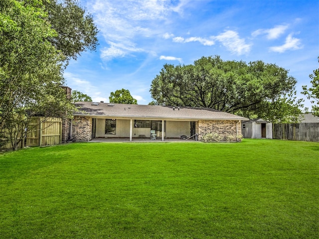 back of property featuring a lawn, a patio area, and a storage shed