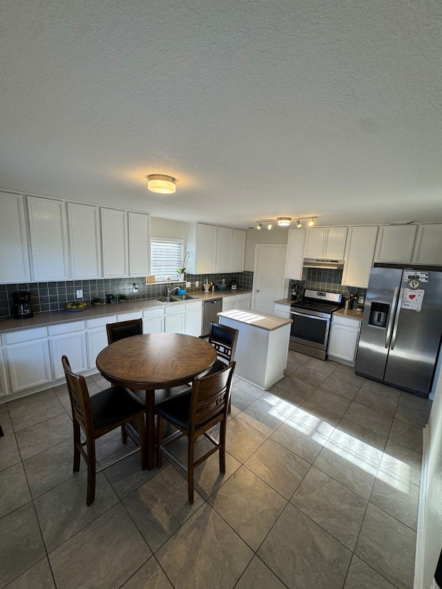 kitchen with decorative backsplash, stainless steel appliances, a kitchen island, and white cabinetry