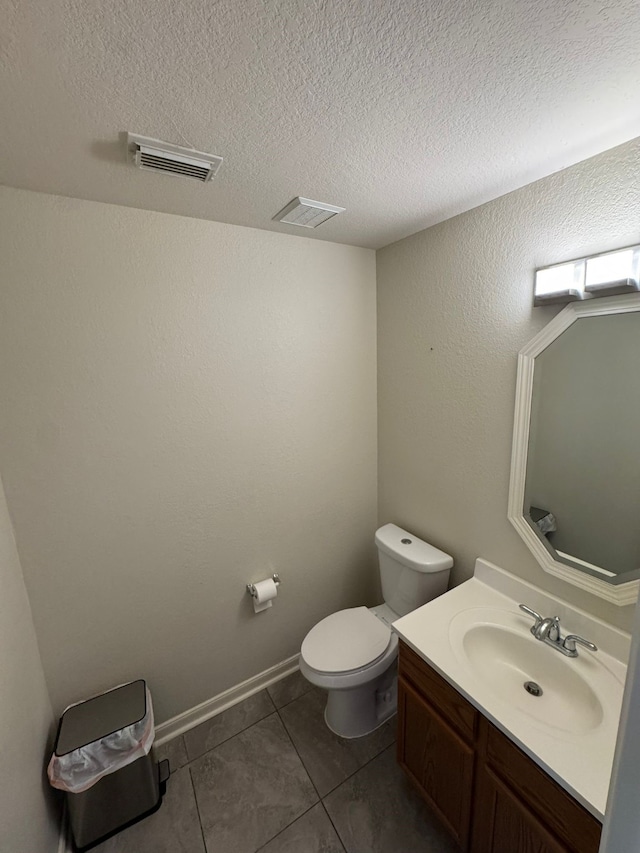 bathroom with tile patterned floors, vanity, a textured ceiling, and toilet