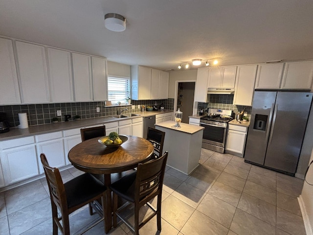 kitchen featuring backsplash, stainless steel appliances, sink, light tile patterned floors, and white cabinets