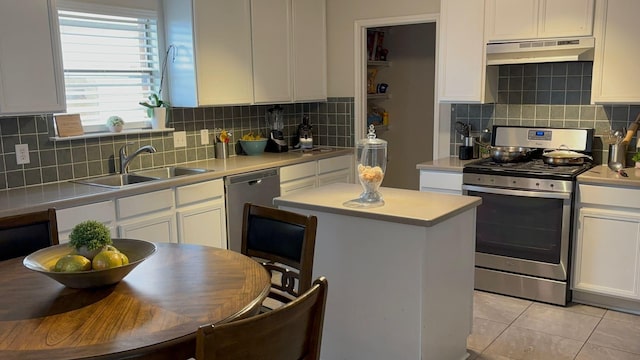 kitchen featuring exhaust hood, sink, appliances with stainless steel finishes, light tile patterned flooring, and white cabinetry