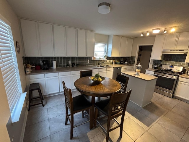 kitchen featuring light tile patterned floors, a center island, stainless steel appliances, and white cabinetry