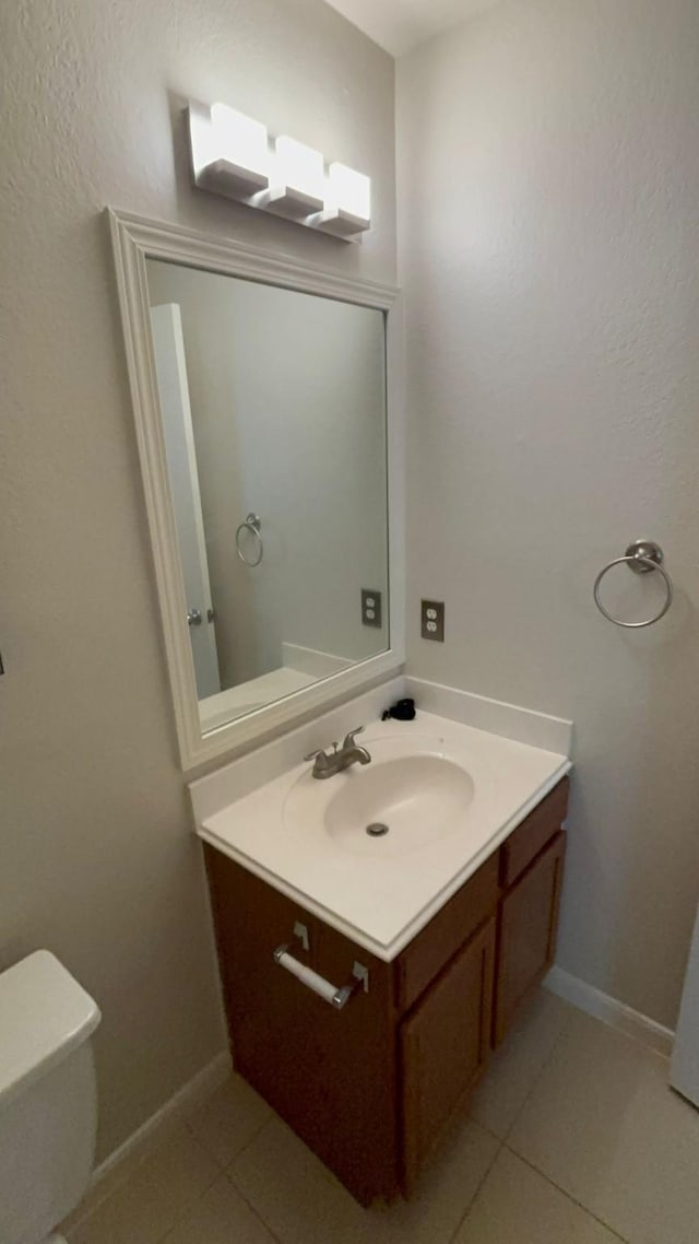 bathroom with toilet, vanity, and tile patterned floors