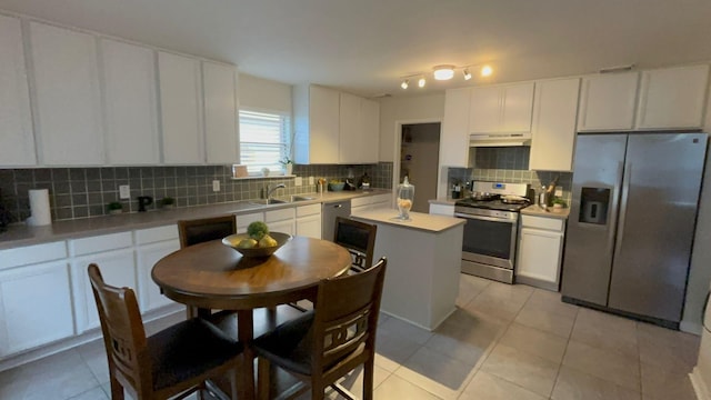 kitchen featuring appliances with stainless steel finishes, sink, light tile patterned floors, white cabinets, and a center island