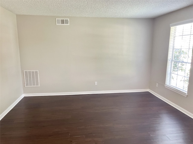 spare room featuring dark hardwood / wood-style flooring and a textured ceiling