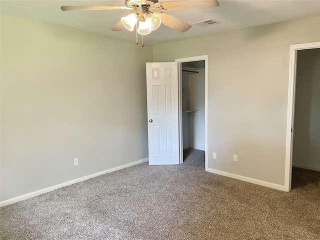 unfurnished bedroom featuring a walk in closet, ceiling fan, a closet, and carpet