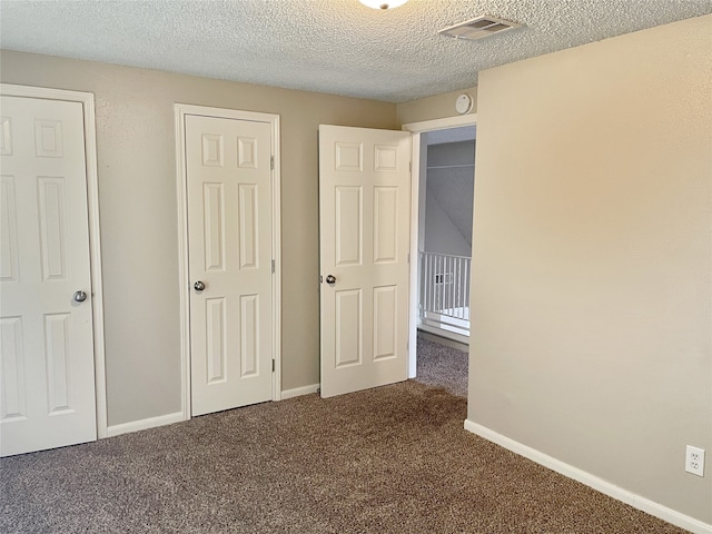 unfurnished bedroom featuring a textured ceiling and dark carpet