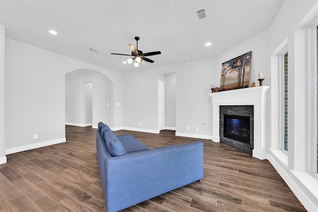 living room featuring a stone fireplace, ceiling fan, and dark hardwood / wood-style flooring