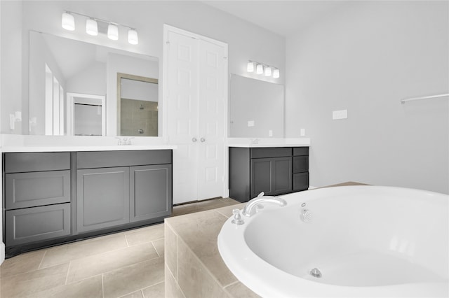 bathroom with tile patterned flooring, vanity, and tiled tub