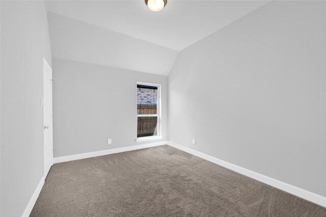 carpeted empty room featuring vaulted ceiling