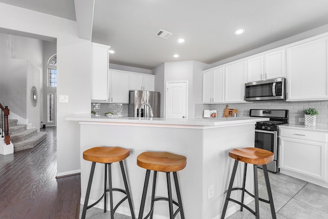 kitchen with white cabinets, stainless steel appliances, and light hardwood / wood-style flooring