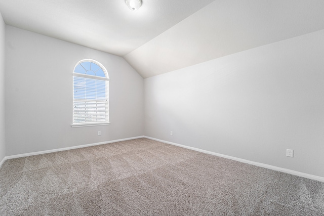 carpeted spare room with lofted ceiling