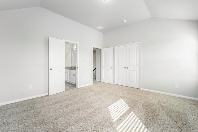 unfurnished bedroom with light carpet, ensuite bathroom, vaulted ceiling, and a closet