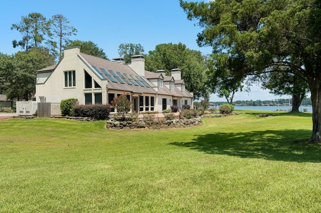 back of house with a water view and a yard