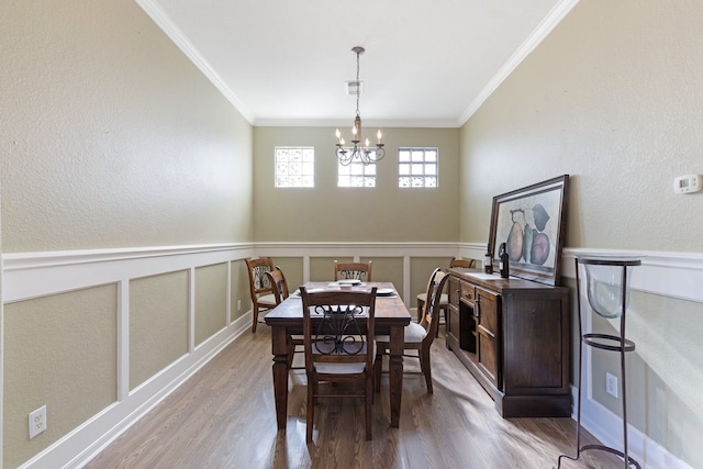 dining space featuring a chandelier, light wood-type flooring, and crown molding