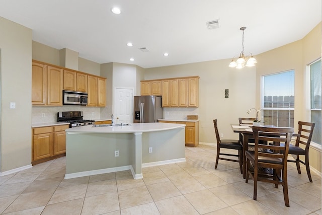 kitchen featuring sink, stainless steel appliances, a notable chandelier, pendant lighting, and a center island with sink