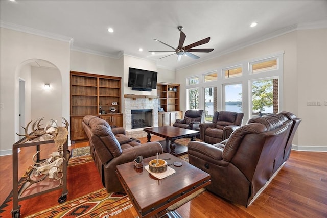 living room featuring a fireplace, ceiling fan, crown molding, and dark wood-type flooring