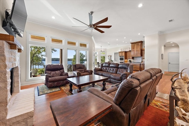 living room featuring dark hardwood / wood-style floors, a fireplace, crown molding, and ceiling fan