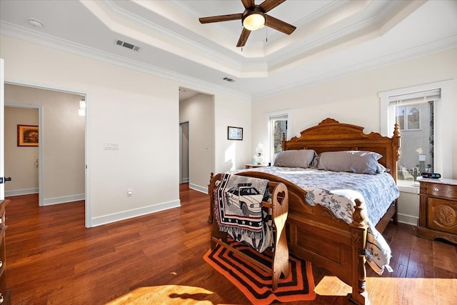 bedroom with a raised ceiling, ceiling fan, crown molding, and dark wood-type flooring