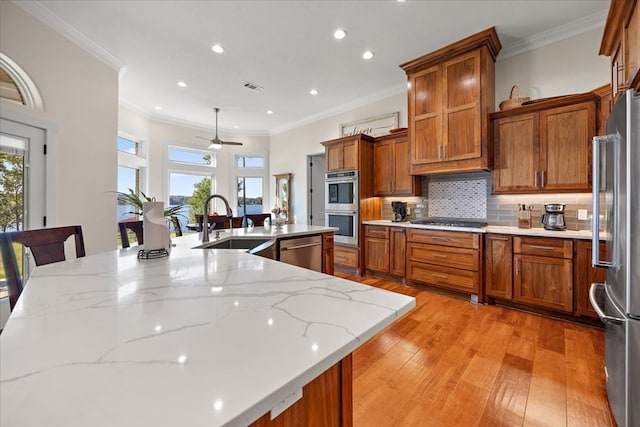 kitchen with a healthy amount of sunlight, a kitchen bar, light wood-type flooring, and appliances with stainless steel finishes