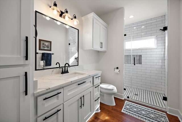 bathroom with a shower with door, vanity, wood-type flooring, and toilet