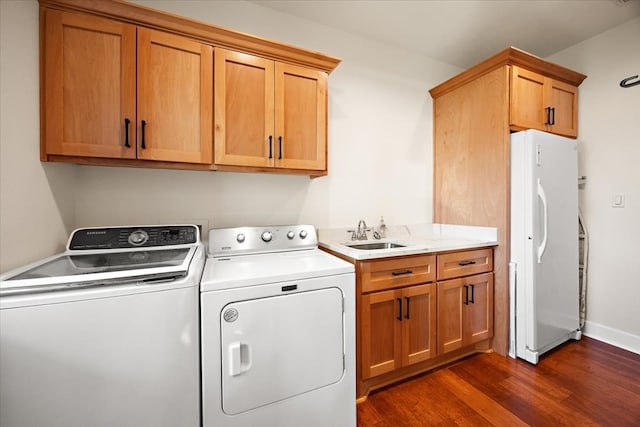 clothes washing area featuring cabinets, dark hardwood / wood-style flooring, washer and clothes dryer, and sink