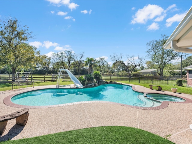 view of swimming pool with a lawn, a patio area, an in ground hot tub, and a water slide