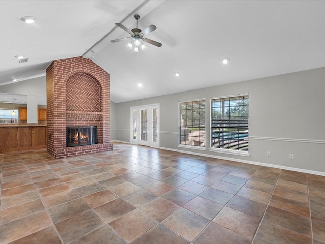 unfurnished living room with french doors, a brick fireplace, tile patterned floors, ceiling fan, and lofted ceiling with beams