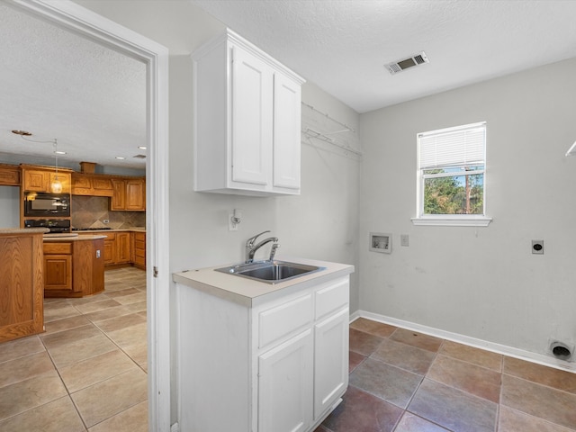 washroom with hookup for an electric dryer, hookup for a washing machine, cabinets, a textured ceiling, and sink