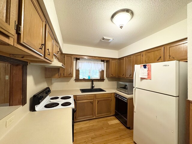kitchen featuring dishwasher, sink, white refrigerator, a textured ceiling, and light wood-type flooring