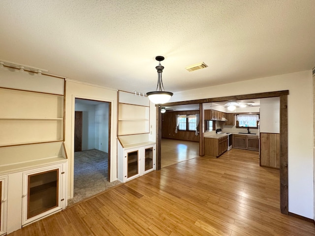 unfurnished living room featuring wood walls, hardwood / wood-style floors, a textured ceiling, and sink