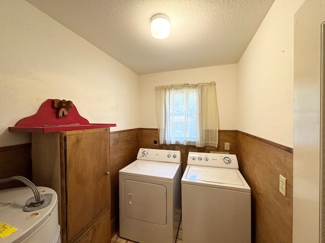 laundry area featuring a textured ceiling, washing machine and dryer, tile walls, and water heater