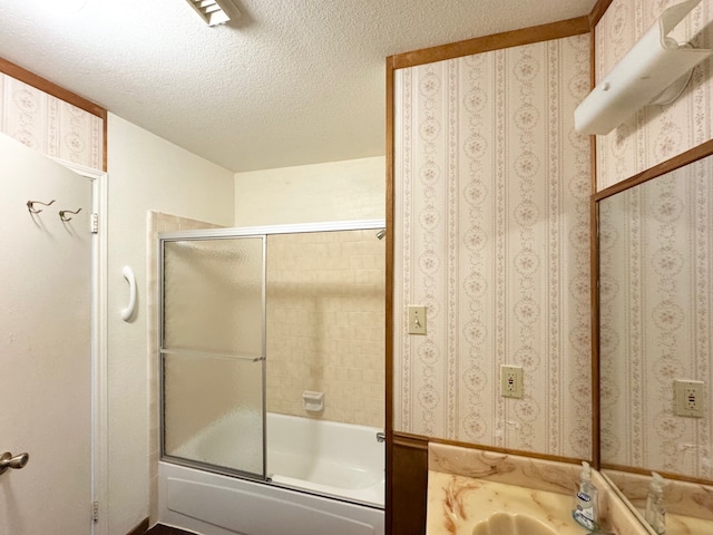 bathroom featuring shower / bath combination with glass door, vanity, and a textured ceiling