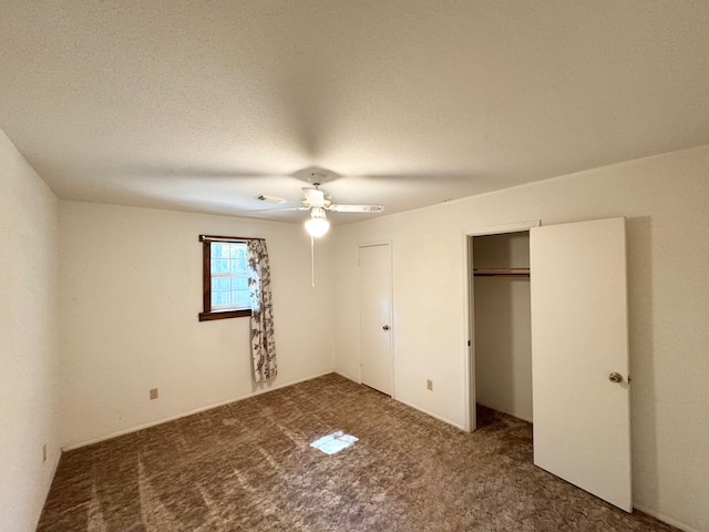 unfurnished bedroom featuring dark colored carpet, a textured ceiling, and ceiling fan
