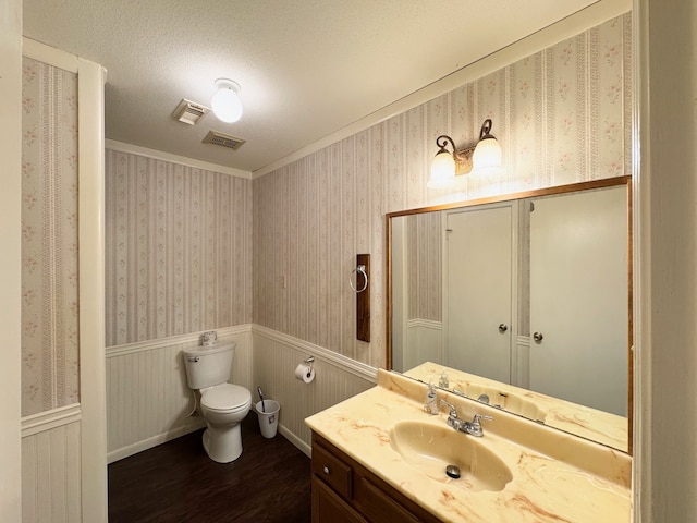 bathroom featuring hardwood / wood-style floors, vanity, crown molding, toilet, and a textured ceiling