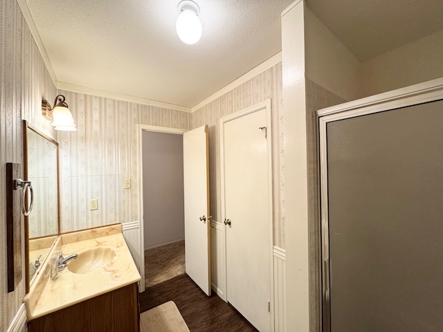 bathroom with walk in shower, vanity, a textured ceiling, crown molding, and hardwood / wood-style floors