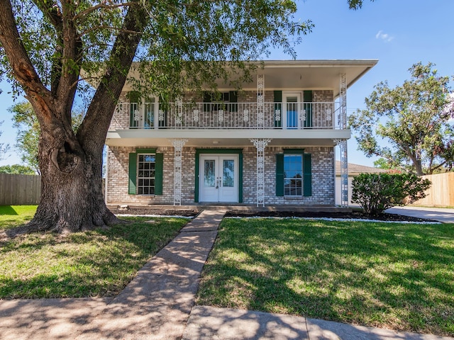 view of front of home featuring a front lawn, french doors, a balcony, and a porch