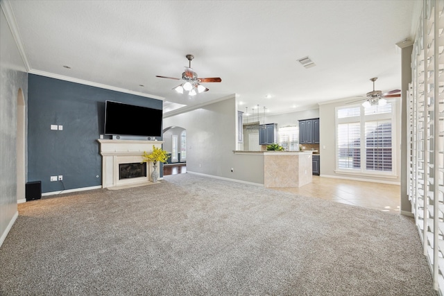 unfurnished living room featuring carpet flooring, ceiling fan, and ornamental molding