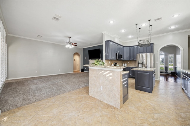 kitchen with a center island, crown molding, ceiling fan, appliances with stainless steel finishes, and light tile patterned flooring