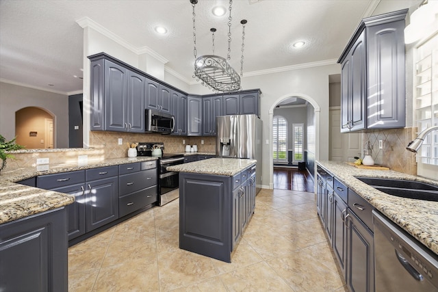 kitchen with light stone countertops, sink, ornamental molding, and appliances with stainless steel finishes