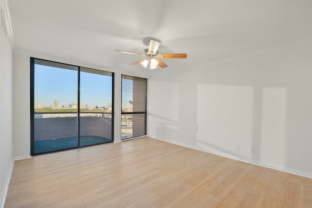 spare room featuring ceiling fan, expansive windows, ornamental molding, and light hardwood / wood-style flooring