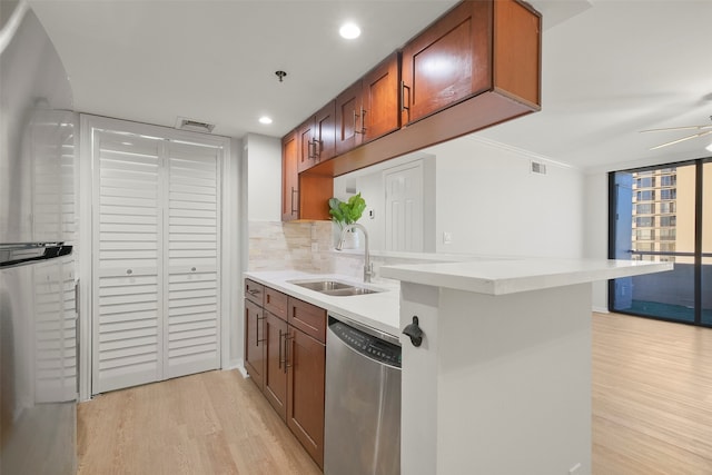 kitchen featuring stainless steel dishwasher, kitchen peninsula, sink, and light hardwood / wood-style flooring