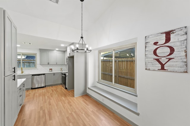 kitchen featuring gray cabinetry, stainless steel appliances, hanging light fixtures, and light hardwood / wood-style flooring