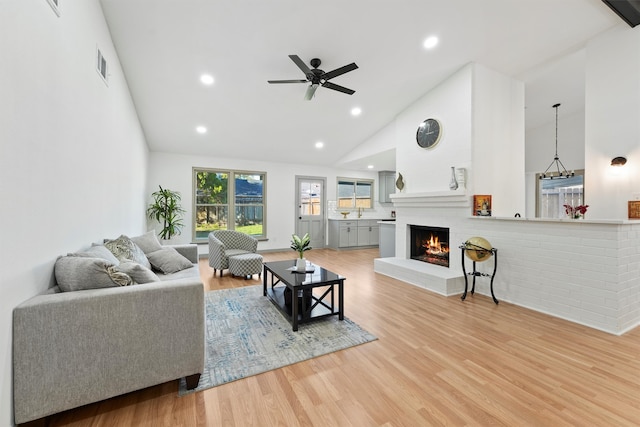 living room with a fireplace, high vaulted ceiling, light hardwood / wood-style flooring, and ceiling fan