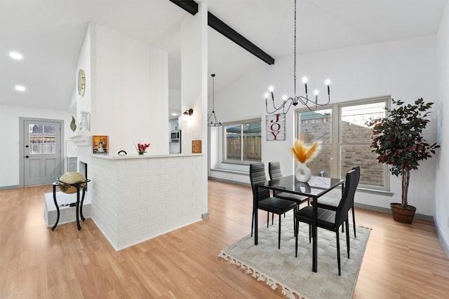 dining room with beam ceiling, a wealth of natural light, light hardwood / wood-style flooring, and an inviting chandelier