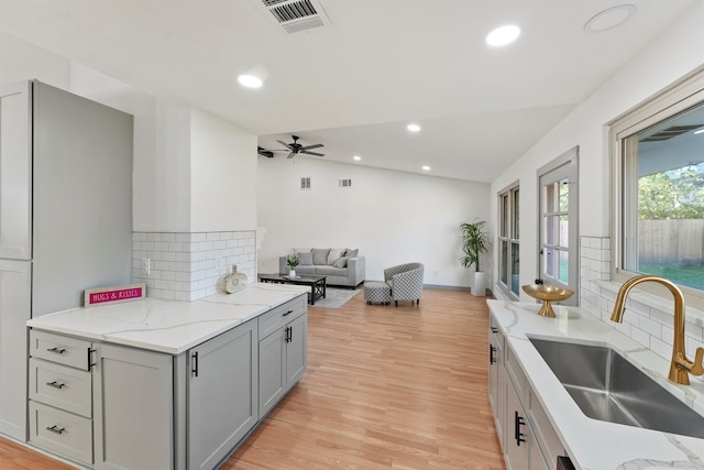 kitchen with backsplash, light hardwood / wood-style floors, gray cabinets, and sink