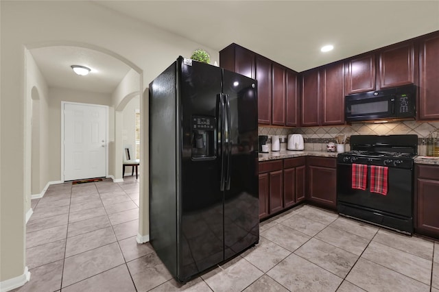 kitchen with light stone countertops, decorative backsplash, light tile patterned flooring, and black appliances