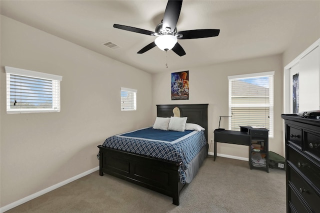 bedroom featuring ceiling fan, light carpet, and multiple windows